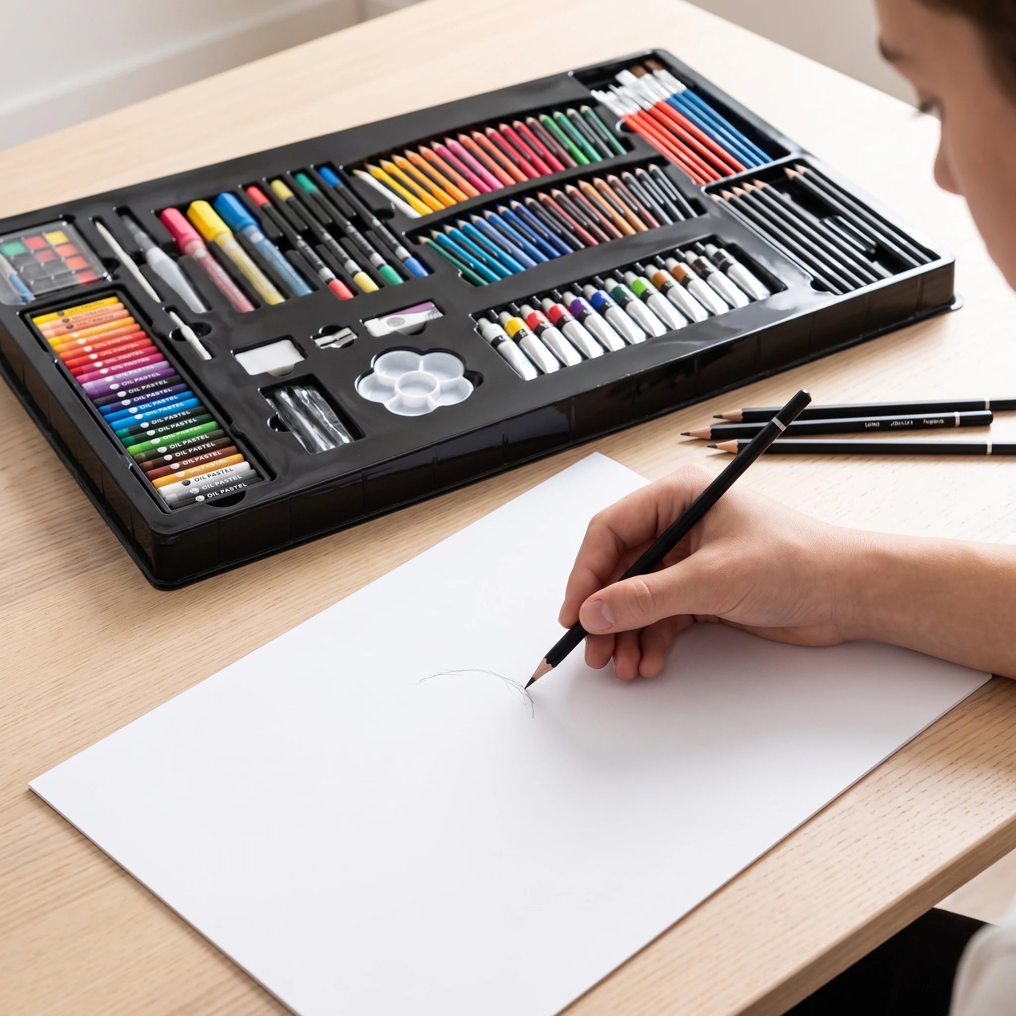 Skicování grafitovou tužkou vedle tácu výtvarné sady
