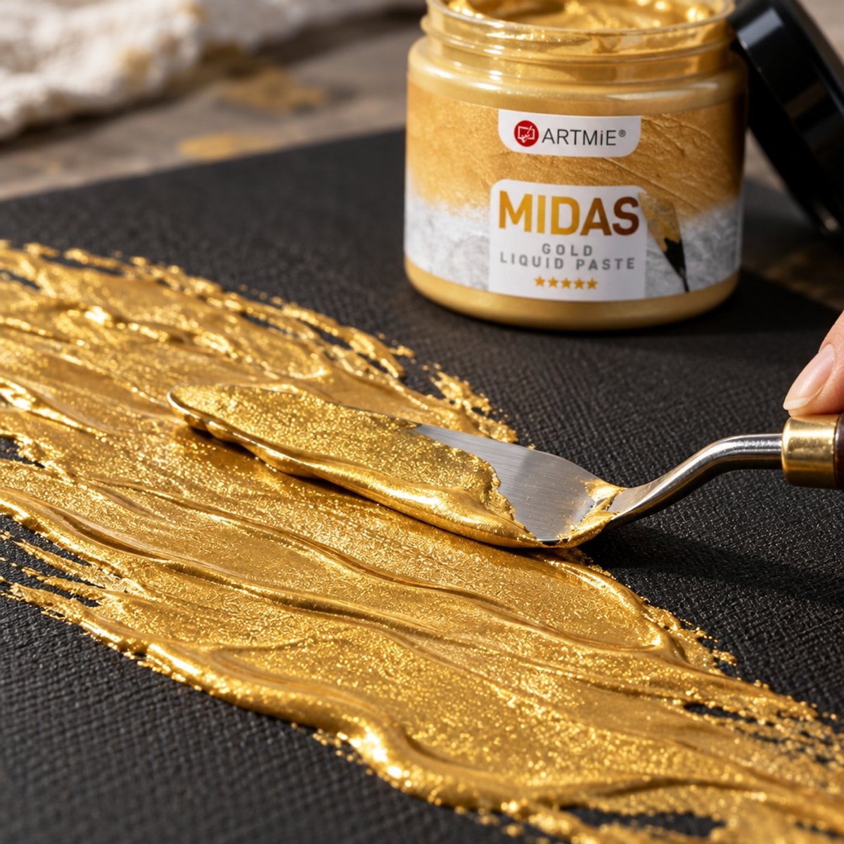 Nanášení zlaté metalické pasty ARTMIE MIDAS špachtlí na černé plátno — makro